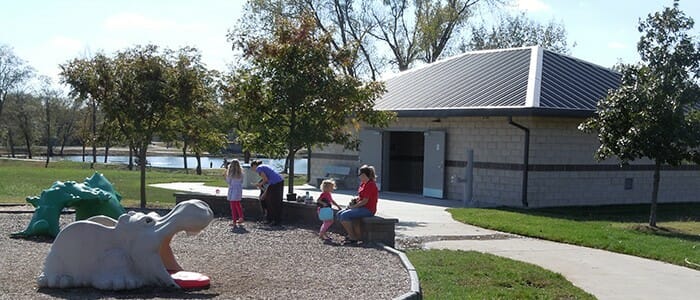 A restroom and storm shelter sitting beside a playground at a park in Kansas