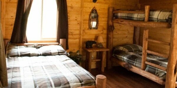 The interior of a cabin with a full bed and bunkbeds