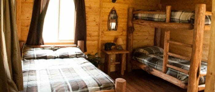 The interior of a cabin with a full bed and bunkbeds